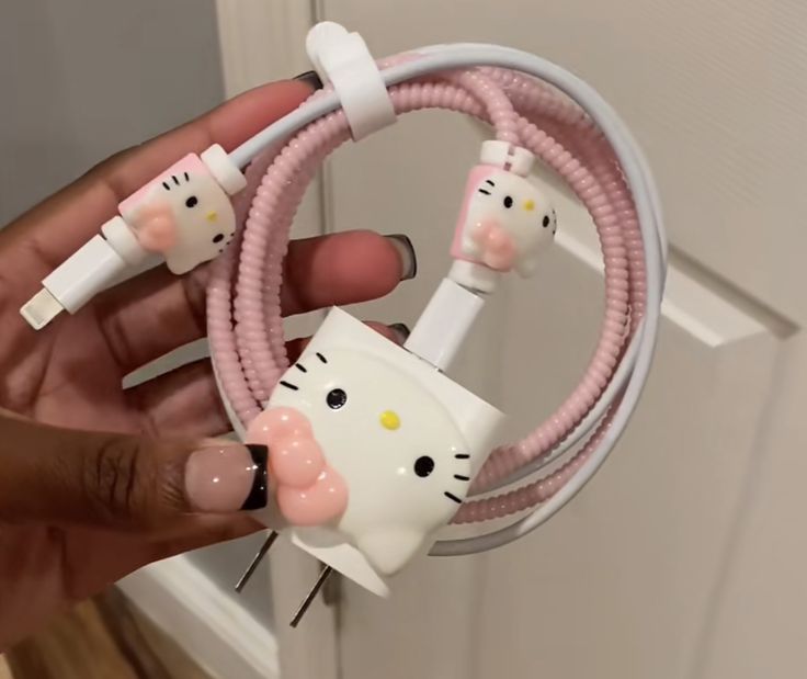 a person holding a hello kitty cable with two cats plugged into the cord and attached to it