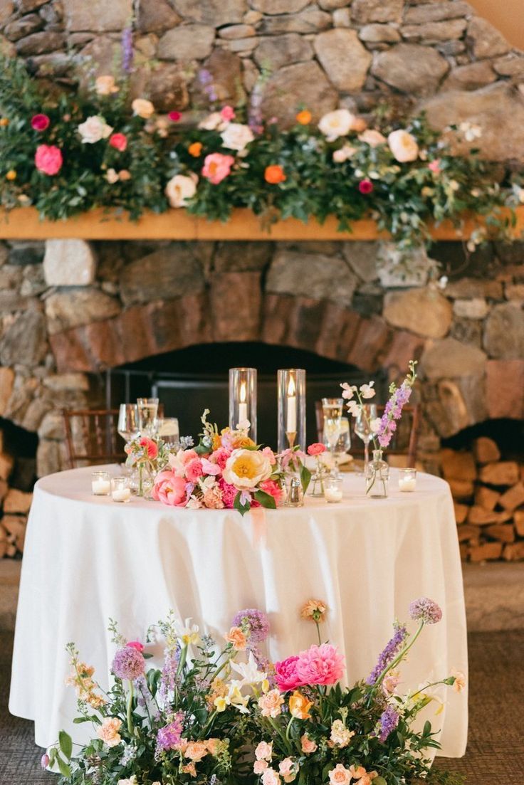 a table with flowers and candles on it next to a fire place in a room