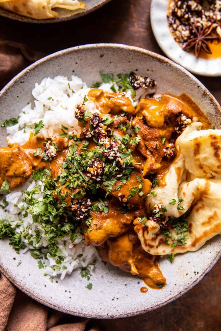 two plates filled with rice and meat covered in sauces, garnished with parsley