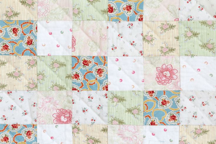 an old patchwork quilt with flowers and leaves on the top, in pastel colors