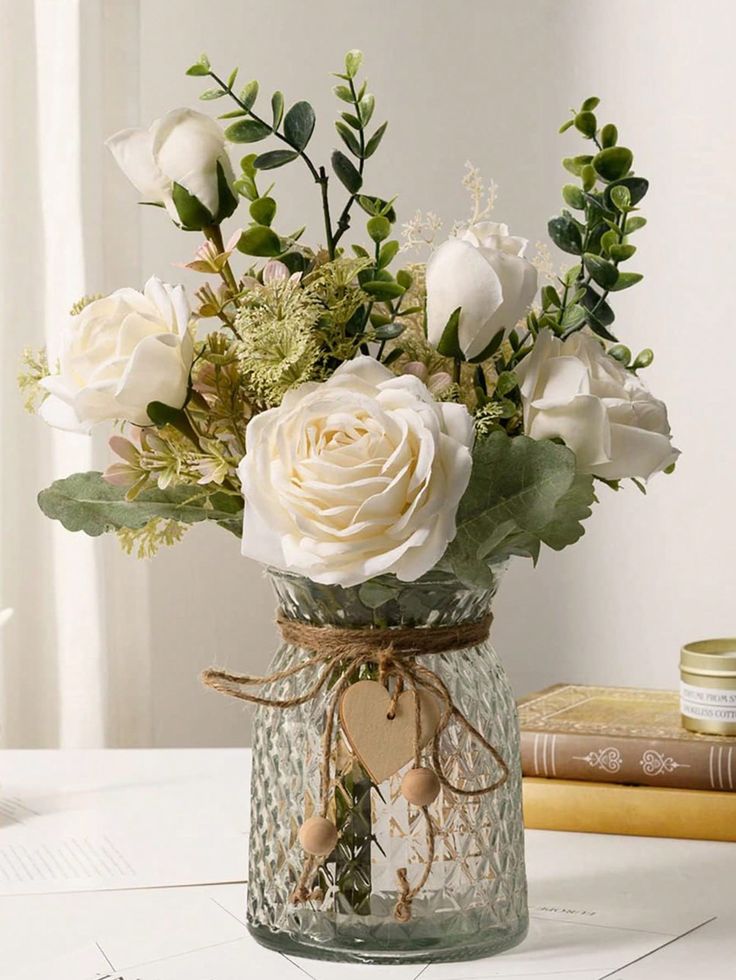 a vase filled with white flowers sitting on top of a table next to a book