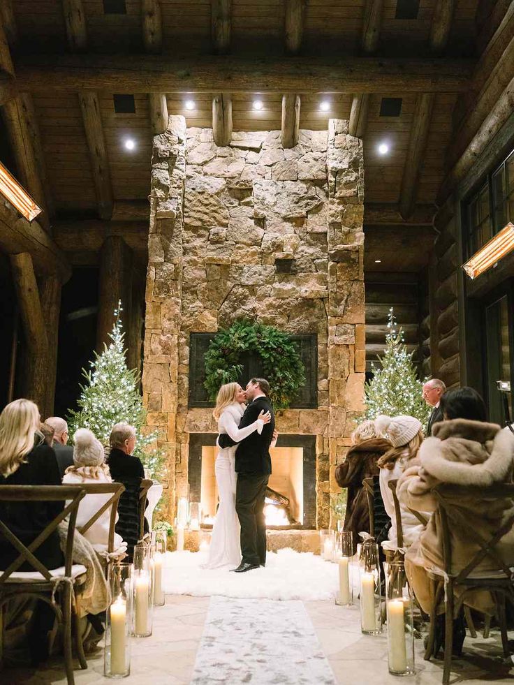 a bride and groom standing at the end of their wedding ceremony in front of a stone fireplace