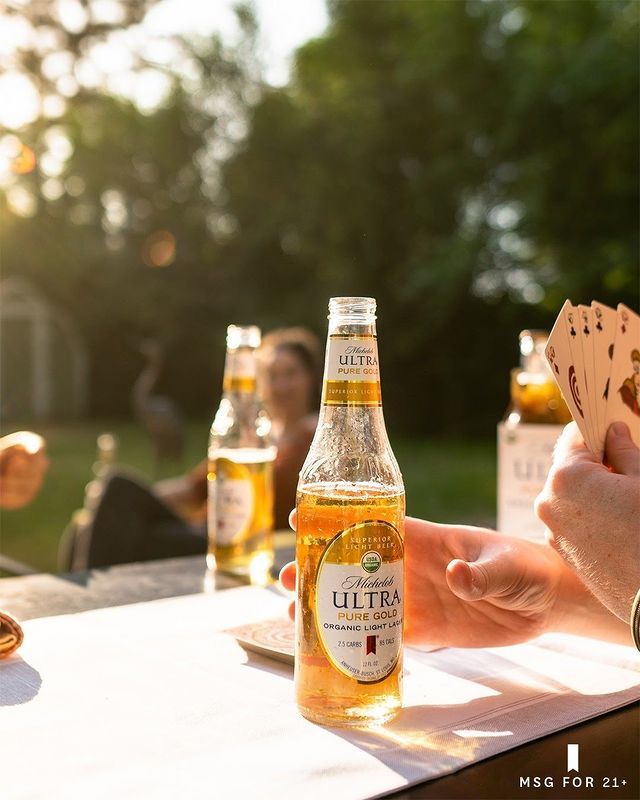 people sitting at a table with beer and cards in front of them on a sunny day