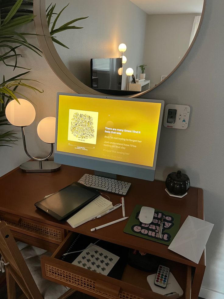 a desk with a computer monitor, keyboard and mouse on it next to a plant