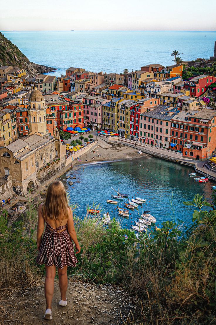 a woman standing on top of a hill next to a body of water with boats in it