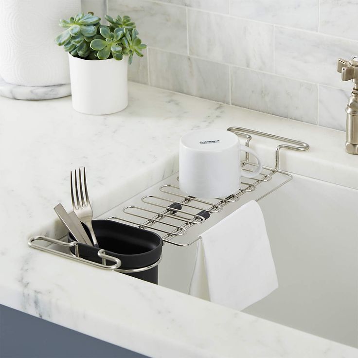 a kitchen sink with utensils in it and a towel rack on the counter