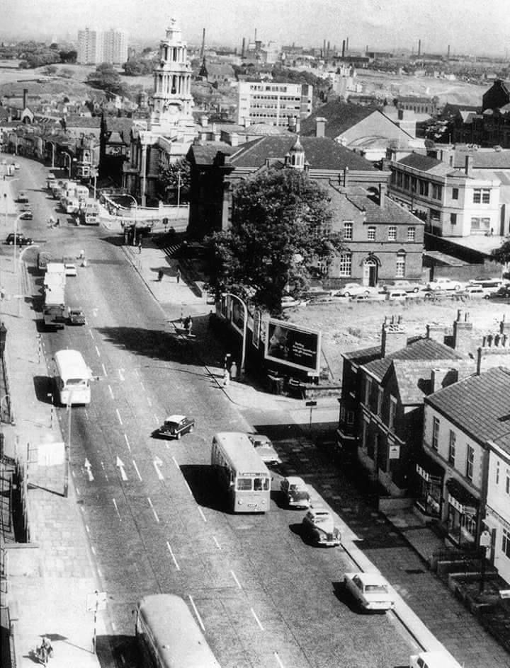 an old black and white photo of a city street with cars parked on the side