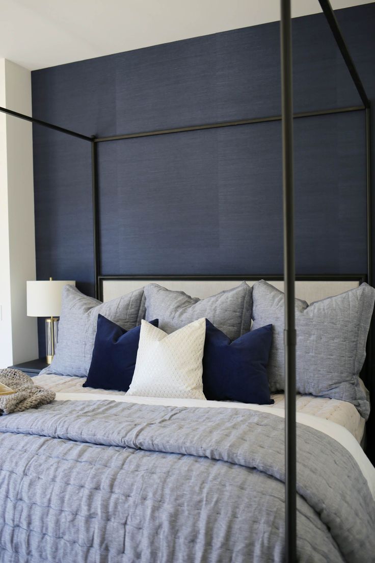 a bed with blue and white pillows in a bedroom next to a wall mounted lamp