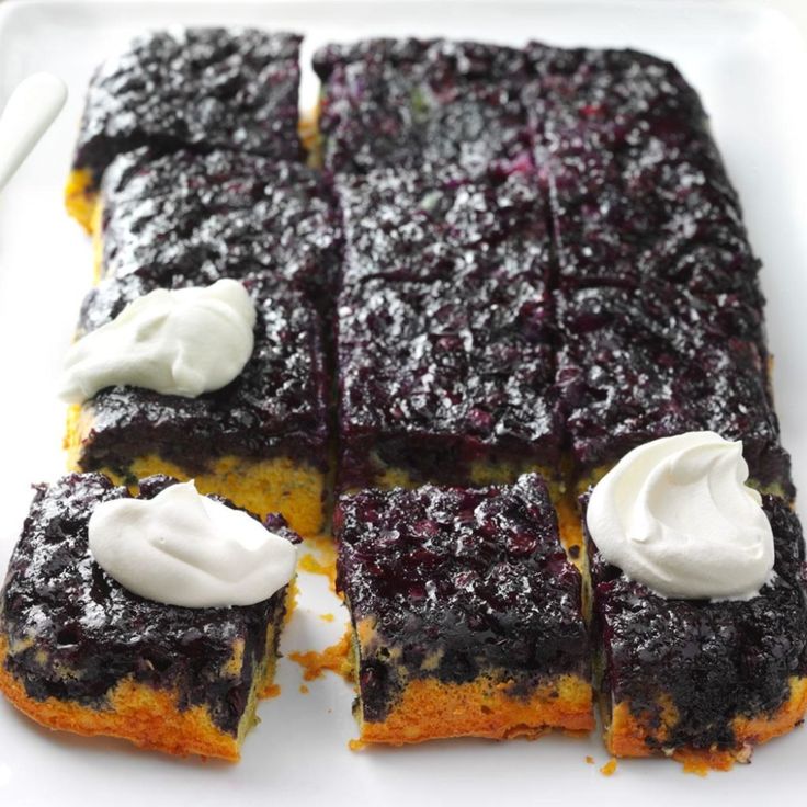 blueberry bars with whipped cream on top are cut into squares and placed on a white plate