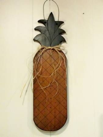 a metal pineapple hanging from the side of a white wall with string attached to it