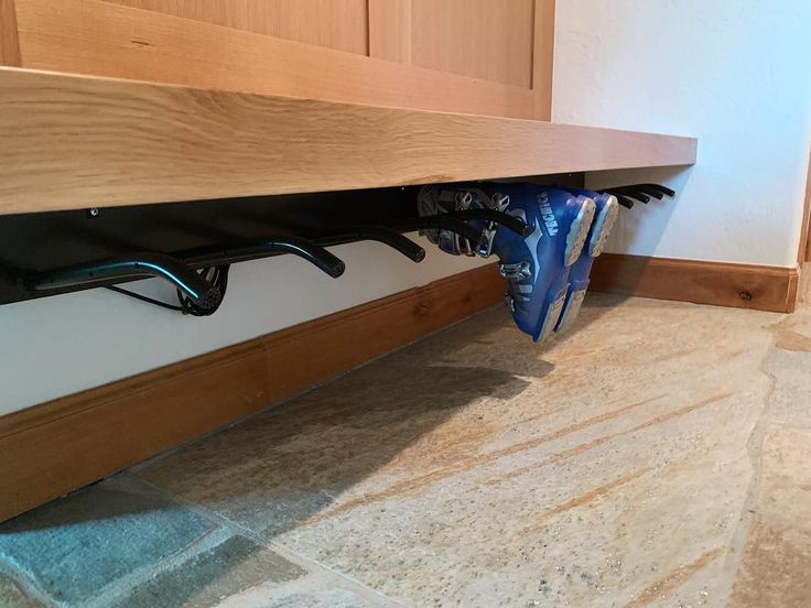 a pair of blue shoes hanging from the side of a wooden shelf in a kitchen