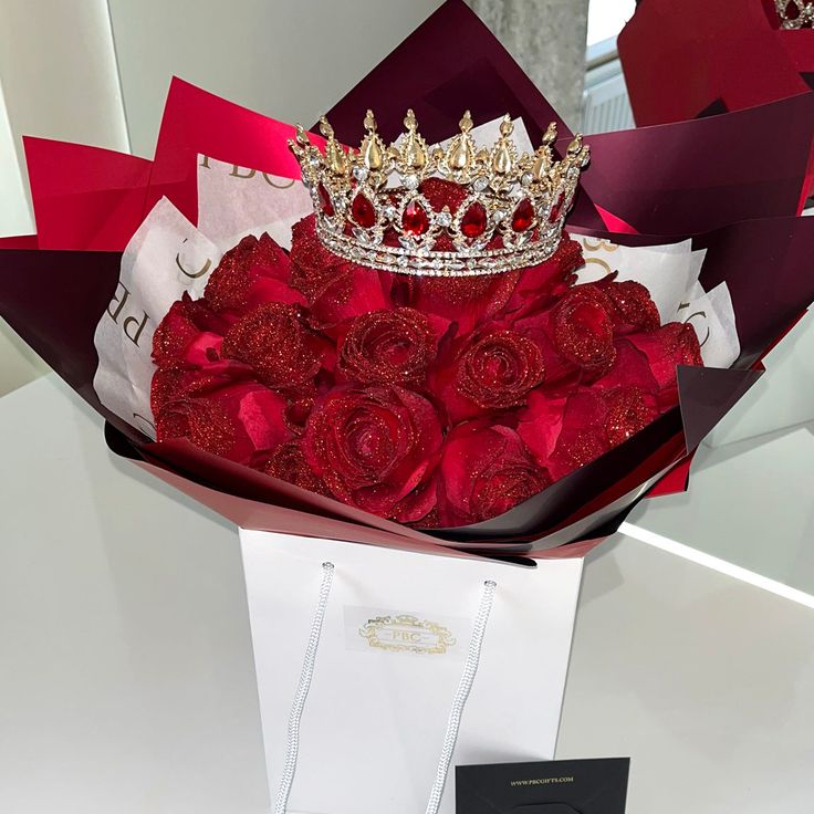 a bouquet of red roses with a crown on top