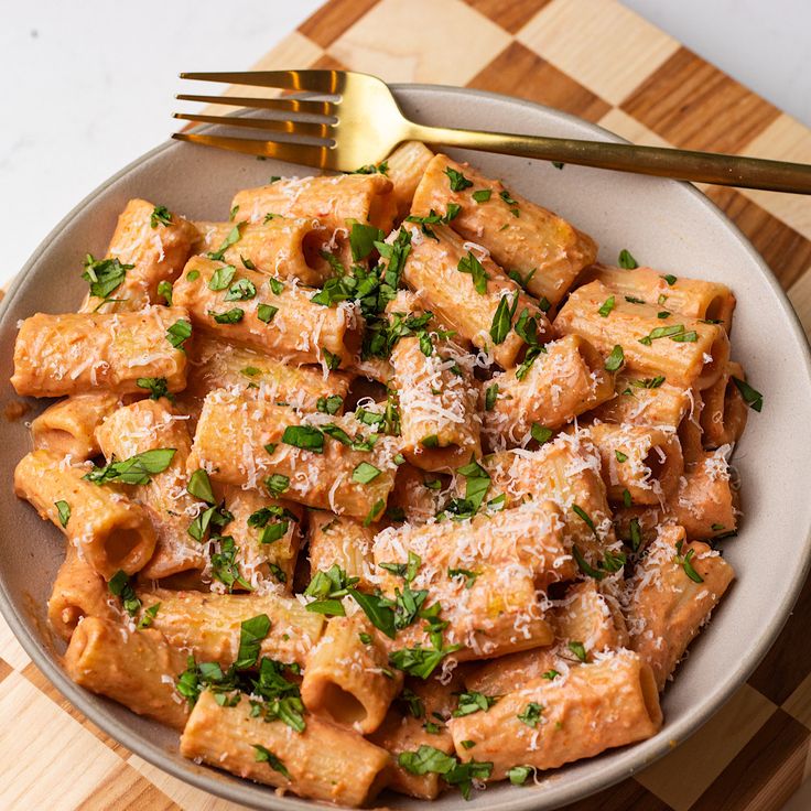 a plate full of pasta with parmesan cheese and herbs on top, next to a fork