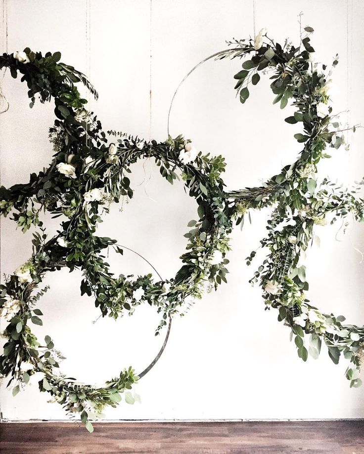 an arrangement of greenery is hanging from the ceiling in front of a white wall