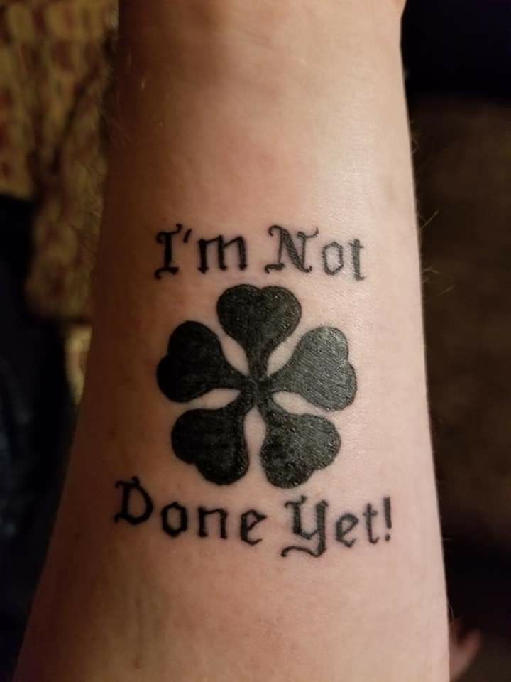 a tattoo that says i'm not done yet with four leaf clovers on it