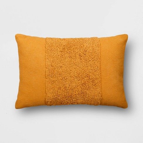 an orange pillow on a white wall with a black border around the edge and a yellow square in the middle