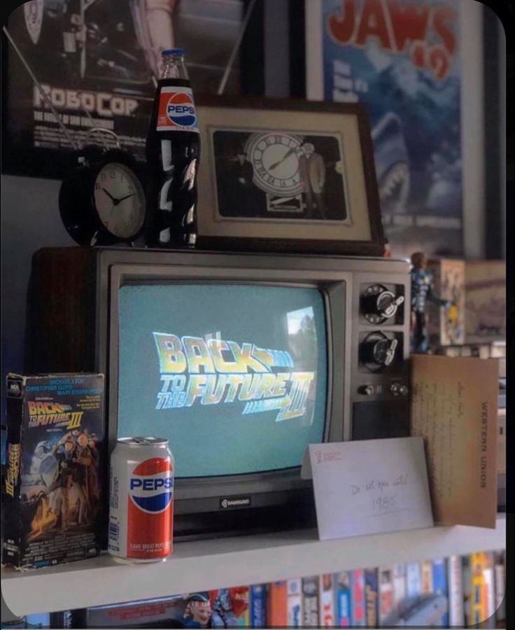 an old tv sitting on top of a book shelf next to a can of soda