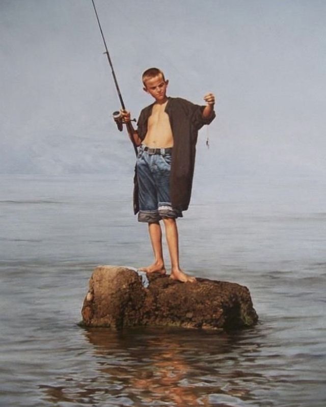 a boy is standing on a rock while holding a fishing rod