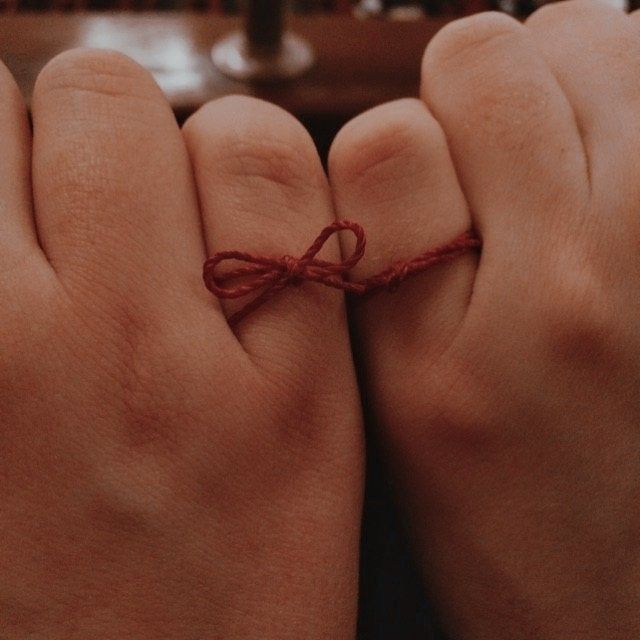 two hands tied together with red string