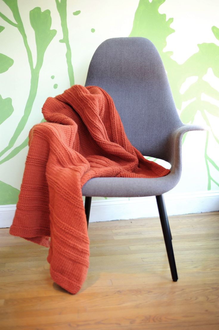 an orange blanket sitting on top of a gray chair