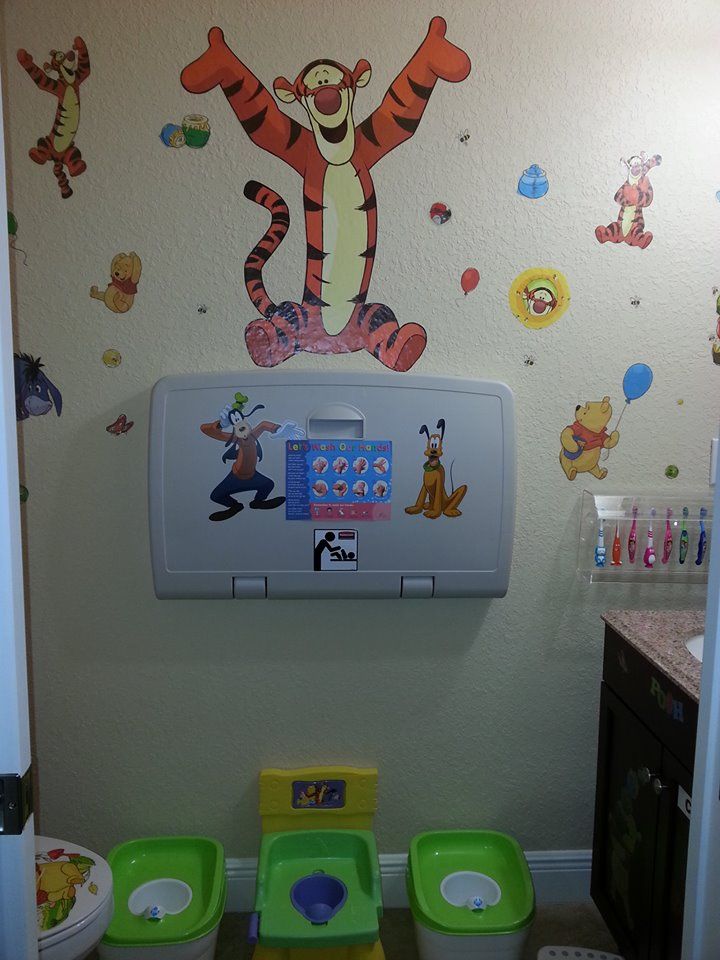 a child's bathroom with winnie the pooh wall decal and toys on the walls