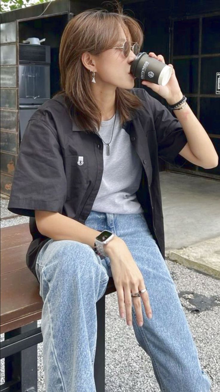 a woman sitting on a bench drinking from a cup