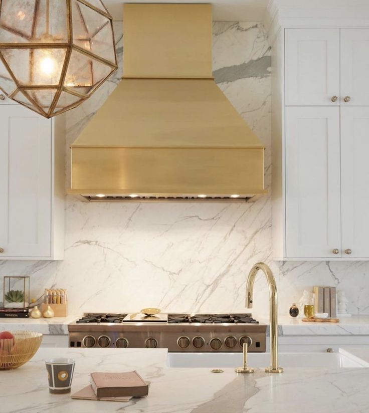 a kitchen with marble counter tops and gold hood