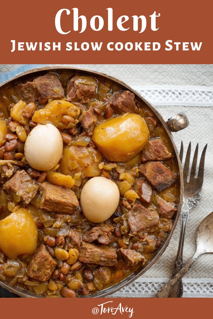 a bowl filled with meat and potatoes next to a fork, knife and spoon on top of