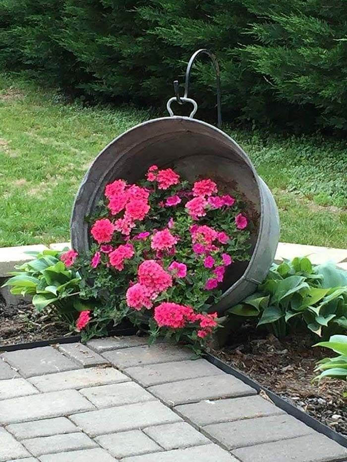 some pink flowers are in a bucket on the ground