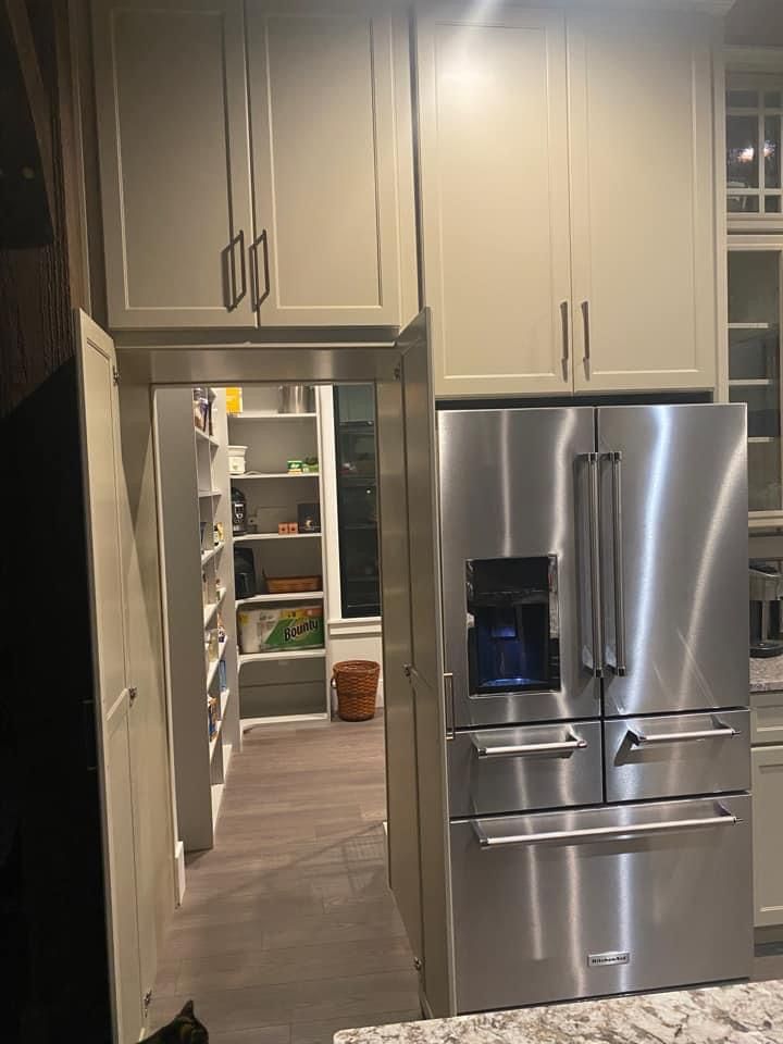 a stainless steel refrigerator in a kitchen with marble counter tops and white cabinetry on the walls