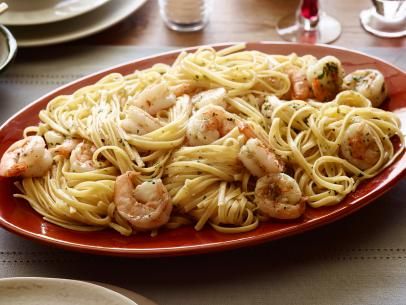 a plate of pasta with shrimp and broccoli on the side at a restaurant