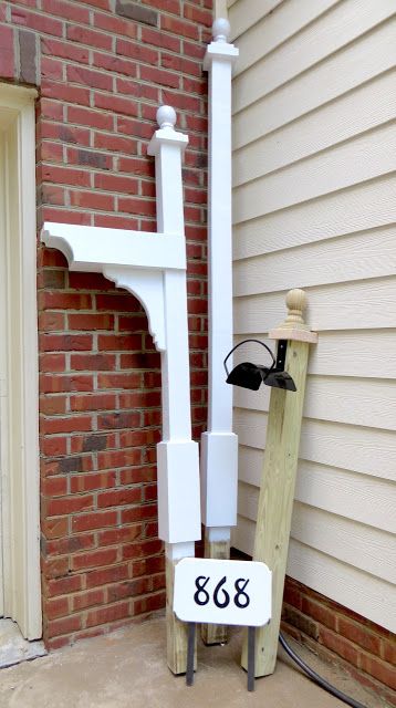 a house number sign in front of a brick building with a white fence and post