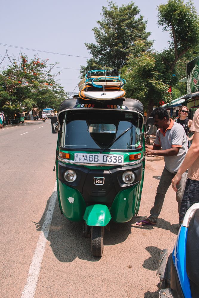 two men standing next to a green and black tuk - tuk