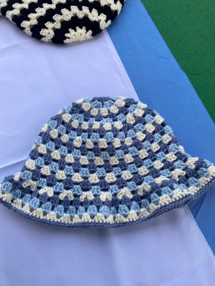 three crocheted hats sitting on top of a blue and white cloth covered table