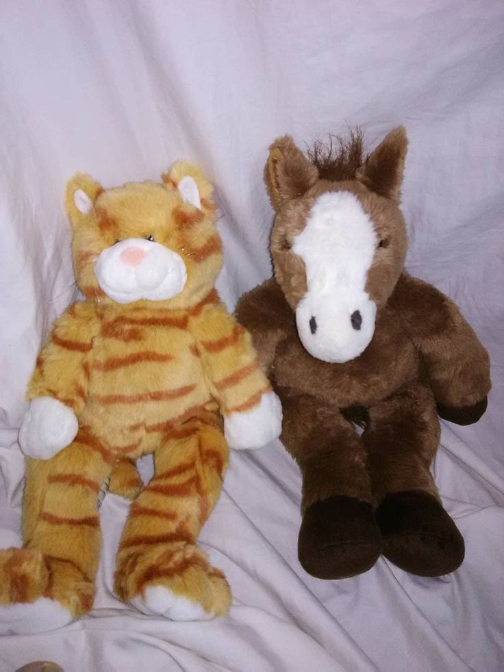 two stuffed animals sitting next to each other on a bed