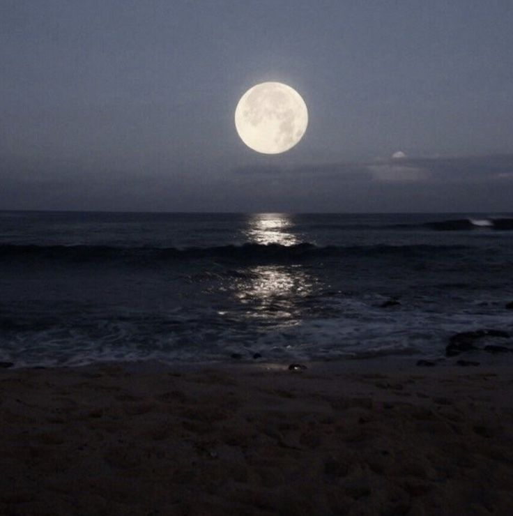 the full moon is shining over the ocean