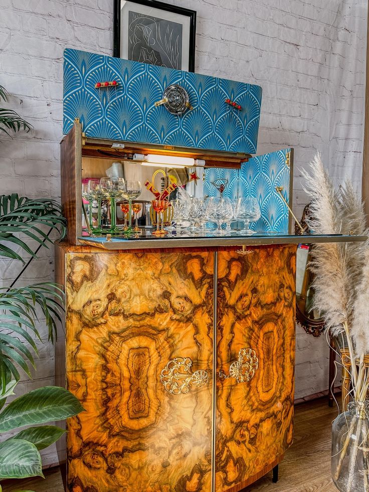 an old fashioned bar with many bottles and glasses on it's front shelf, next to a potted plant