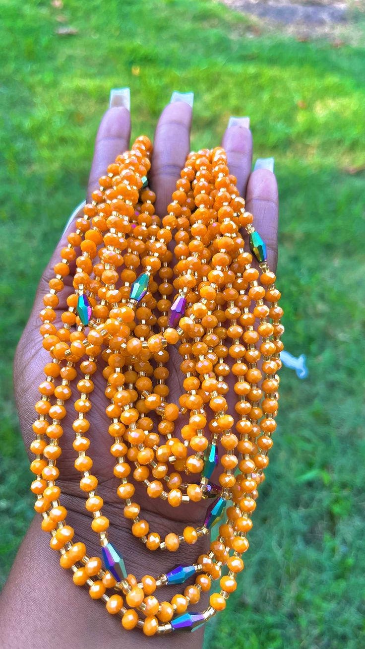 Colors:Orange, Green, Gold, Blue Features: Austrian crystal beads Traditional tie on waist beads Made on 100% African thread Size: approx. 50 inches Priced as individual strand & typically ties once around the waist Orange Faceted Beads, Orange Faceted Oval Beads, Orange Necklaces With Large Beads For Party, Orange Party Necklaces With Large Beads, Traditional Orange Faceted Beads, Traditional Orange Beaded Chain, Orange Faceted Beads Necklace For Party, Large Oval Orange Beads, Orange Large Beads Necklace For Party