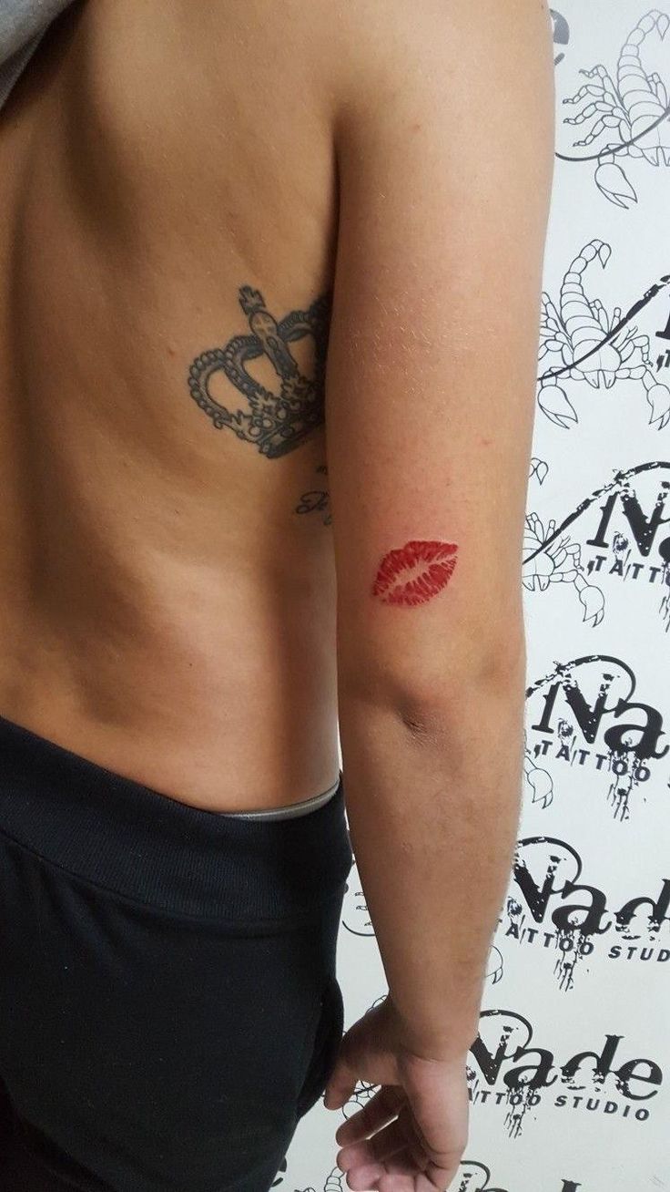 a person with a tattoo on their back and red lipstick painted on the upper part of his arm