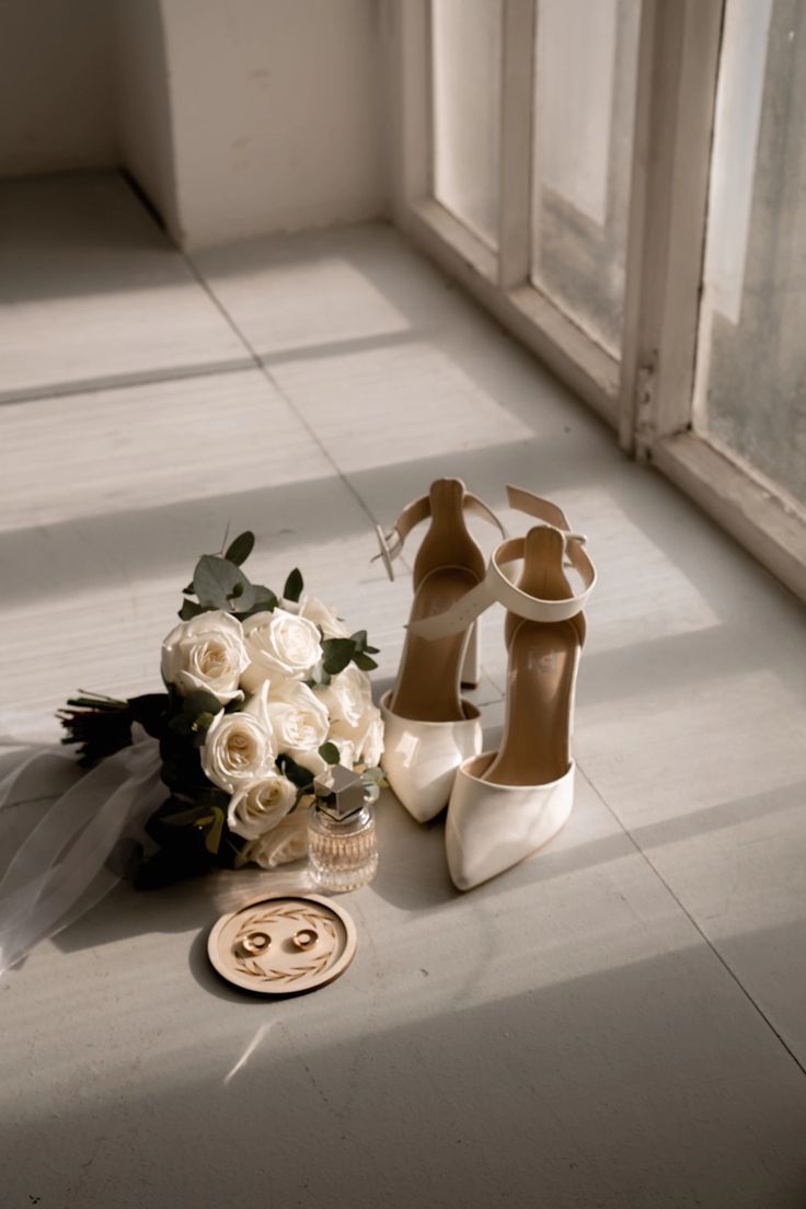 a bouquet of flowers and shoes sitting on the floor next to a pair of heels