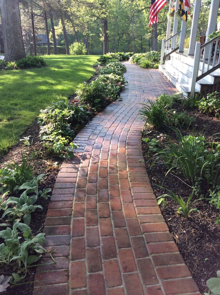 a brick path leading to a porch with an american flag on it