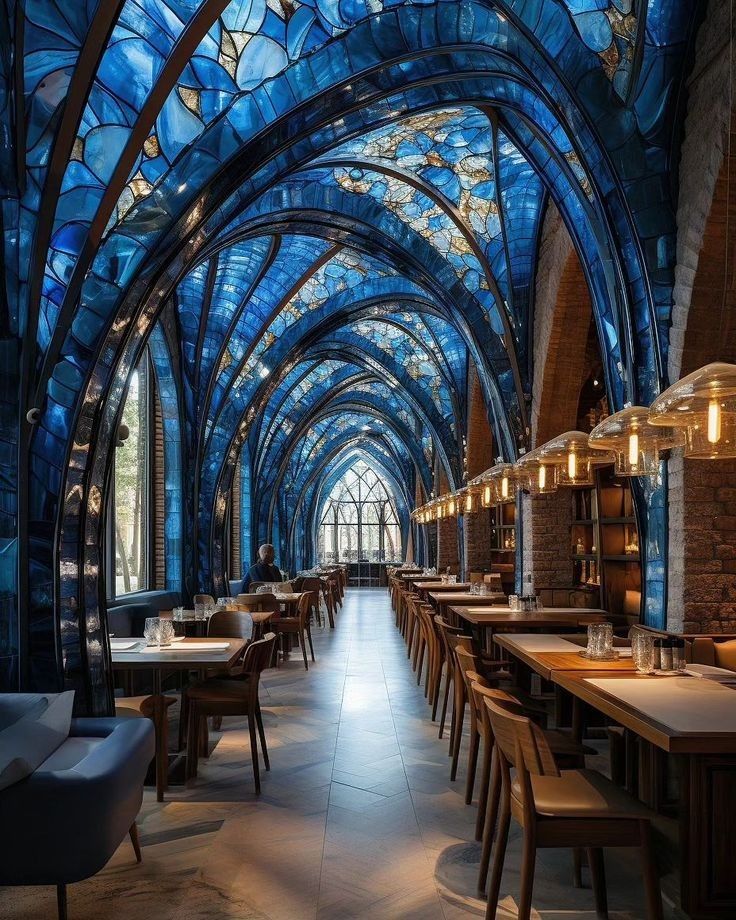 the inside of a restaurant with many tables and chairs, blue stained glass windows on the ceiling