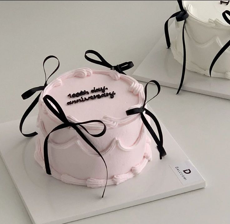 a pink cake with black ribbon on top