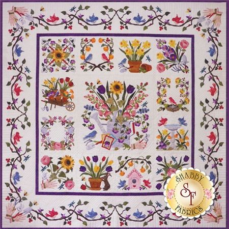 a quilted wall hanging with flowers and birds in the center, on a white background