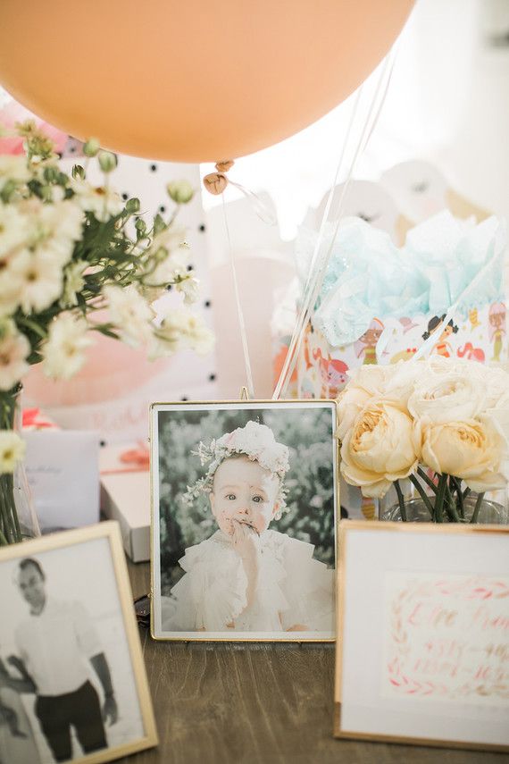 a table topped with pictures and balloons next to flowers on top of a wooden table