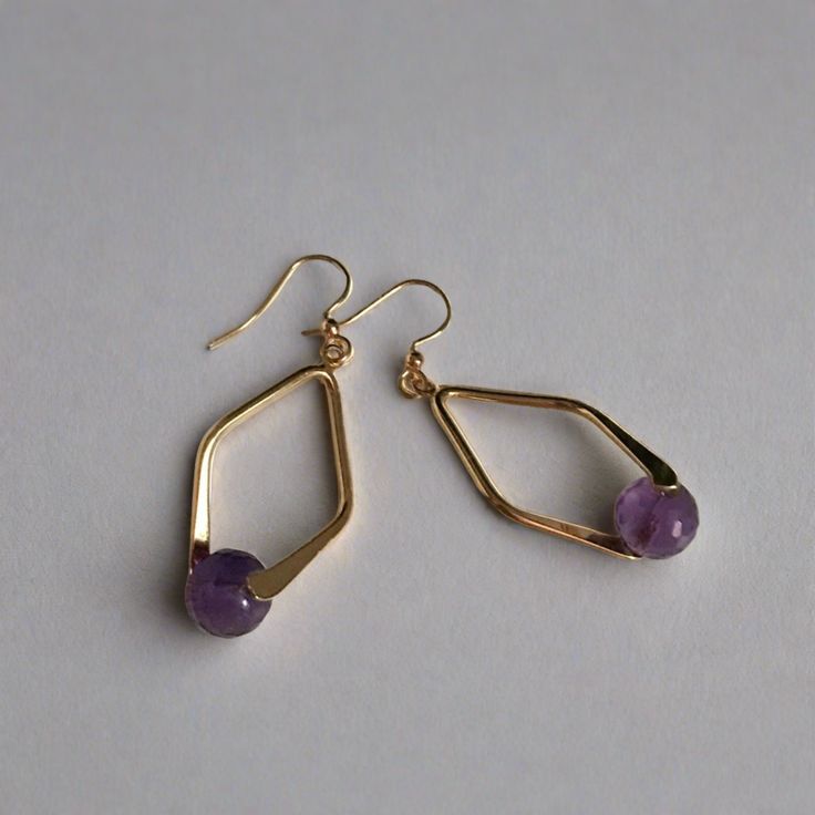 A faceted Amethyst bead set in a double sided diamond shaped frame creates demure drop earrings. 8mm faceted amethyst bead gold plated brass double sided diamond shaped bail gold plated brass french ear wires drop: 2" width: 3/4" Handmade in Lincoln, Nebraska Purple Metal Drop Earrings, Gold Metal Jewelry With Faceted Beads, Gold Crystal Earrings With Faceted Beads, Diamond-shaped Earrings With Ear Wire For Gifts, Faceted Gold Brass Jewelry, Gold Faceted Brass Jewelry, Gold Faceted Crystal Earrings For Gift, Nickel-free Diamond-shaped Jewelry For Gifts, Gold Amethyst Round Earrings