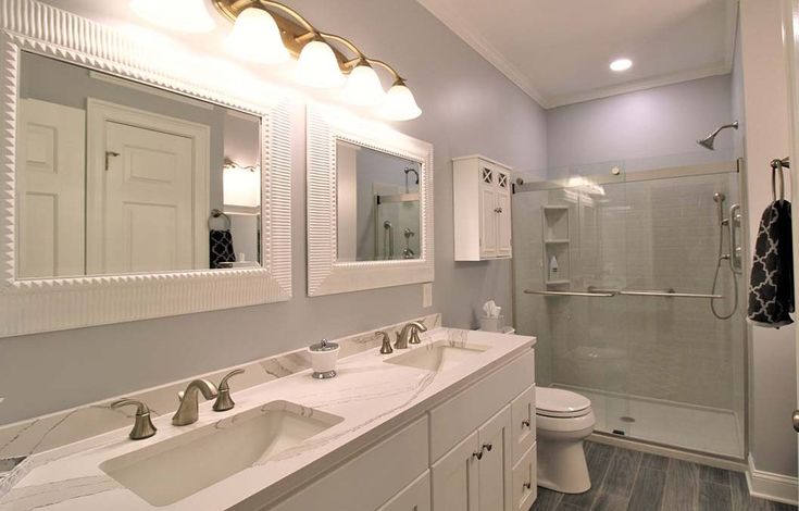 a white bathroom with two sinks and a shower