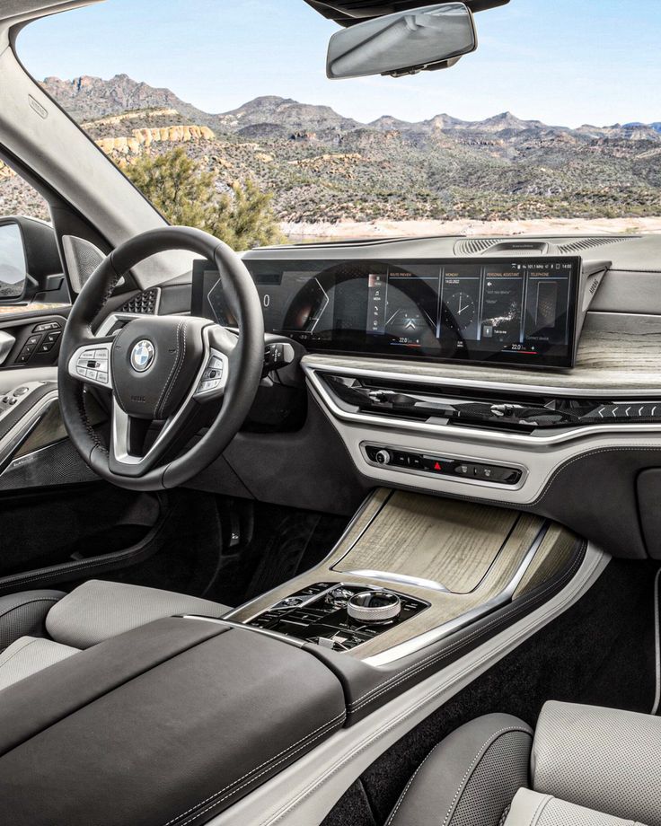 the inside of a car with dashboard, steering wheel and center console in front of mountains