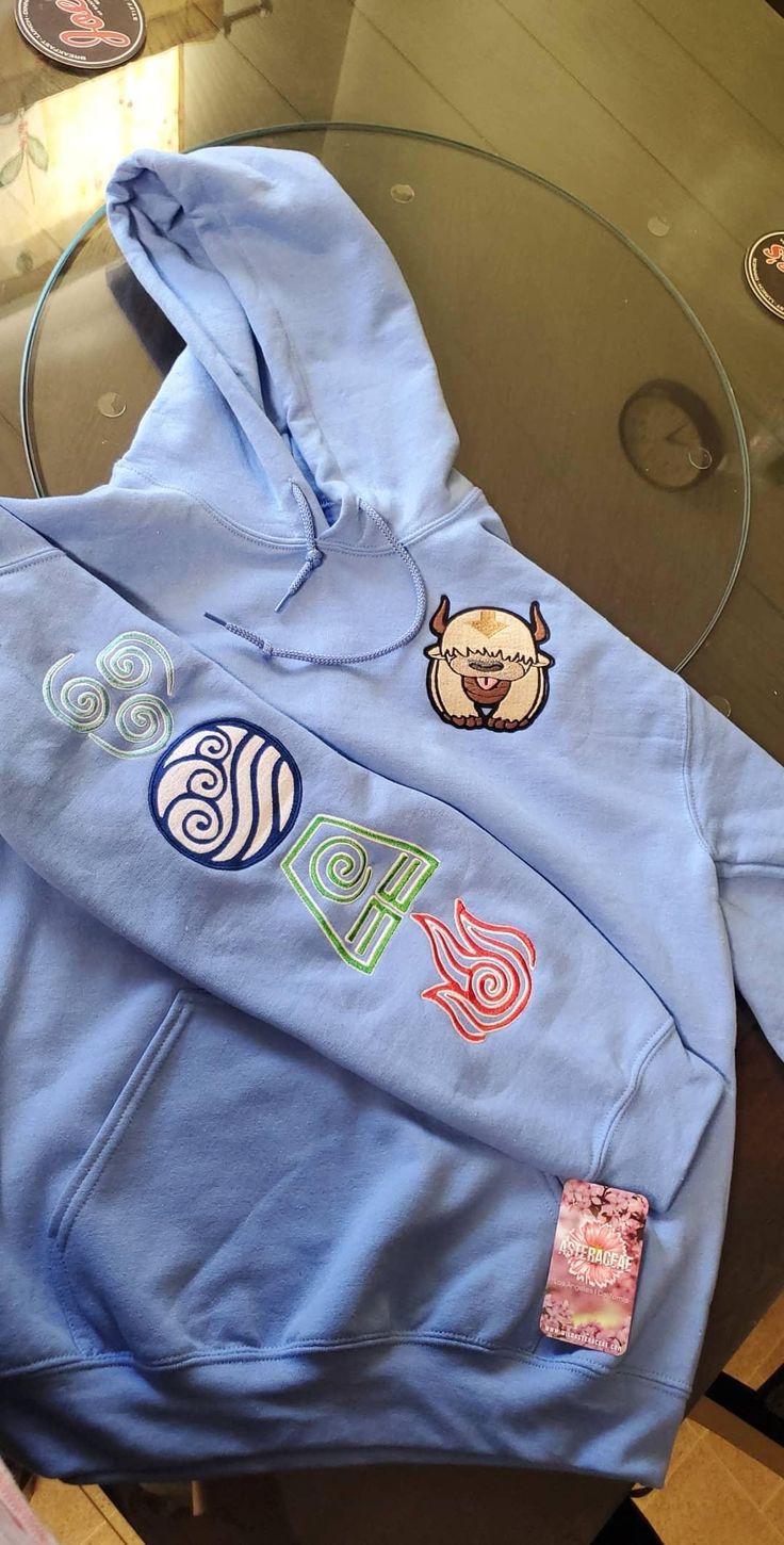 a blue hoodie with various stickers on it sitting on a table next to a glass top