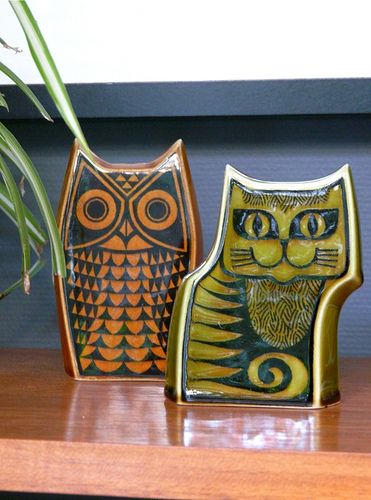 three ceramic owl figurines sitting on a shelf next to a plant in a vase